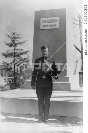 Vintage Portrait of a Soviet Serviceman Holding His Peaked Cap by a Lenin Monument Vintage Portrait of a Soviet Serviceman Holding His Peaked Cap by a Lenin Monument 141301391