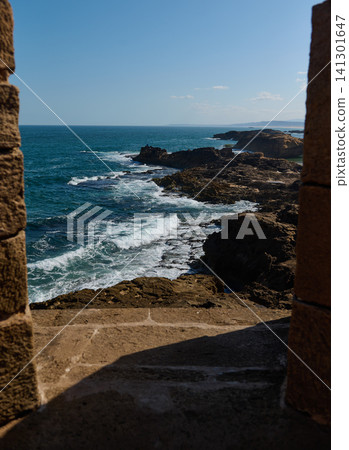 Ocean view from stone arch in Essaouira medina, Morocco overlooking rocky coastline 141301647