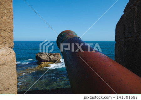 Historic cannon overlooking Atlantic Ocean from Essaouira medina fortress with old city walls and rocky coast 141301682