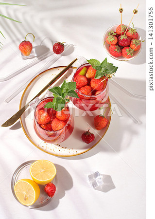 Refreshing summer homemade lemonade cocktail and non-alcoholic mojito, strawberry iced tea with berries, mint and lemon, weight loss concept, detox water with fruit flavor on light background. Refreshing summer homemade lemonade cocktail and non-alcoholic mojito, strawberry iced tea with berries, mint and lemon, weight loss concept, detox water with fruit flavor on light background. 141301756