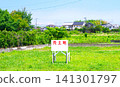 A sign advertising land for sale, surrounded by greenery. 141301797