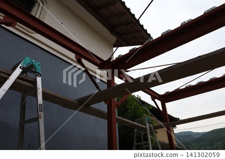 Roofing work and ladders with red steel frames adjacent to an old Japanese building. Roofing work and ladders with red steel frames adjacent to an old Japanese building. 141302059