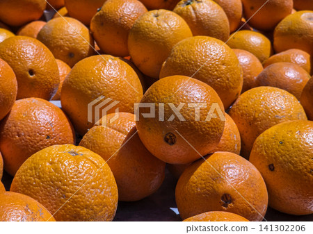 Fresh oranges are stacked high at a fruit market stand in Spain. The oranges have vibrant peels and are ready for customers looking to buy them. Fresh oranges are stacked high at a fruit market stand in Spain. The oranges have vibrant peels and are ready for customers looking to buy them. 141302206