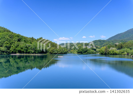 山梨縣上野原市大野水庫鬱鬱蔥蔥的綠植及其在藍天中的倒影。 141302635