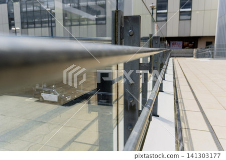 Perspective view of a stylish metal railing and glass fence for a modern outdoor terrace. Perspective view of a stylish metal railing and glass fence for a modern outdoor terrace. 141303177