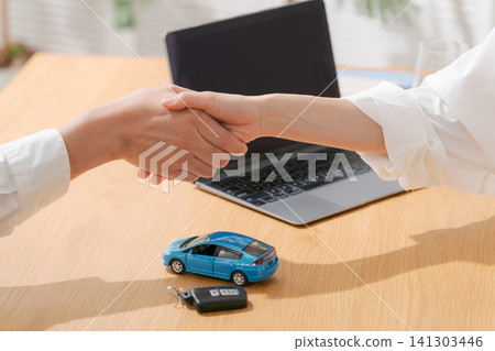 A person shaking hands with a model car 141303446
