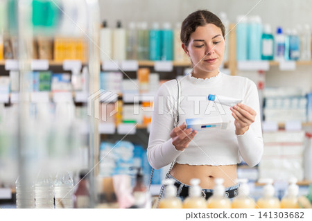 Young woman holding a package of ointment in pharmacy Young woman holding a package of ointment in pharmacy 141303682