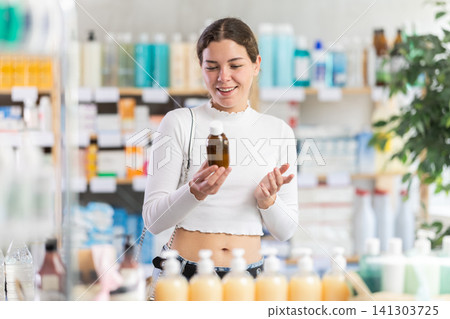 Woman in pharmacy holding a bottle of syrup Woman in pharmacy holding a bottle of syrup 141303725
