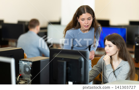 During computer lesson, female teacher helps girl student complete difficult task During computer lesson, female teacher helps girl student complete difficult task 141303727