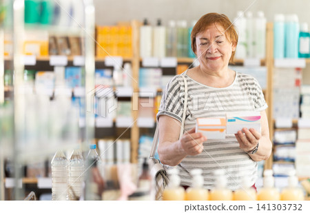 Ederly woman in summer clothes looking for medicine in pharmacy Ederly woman in summer clothes looking for medicine in pharmacy 141303732