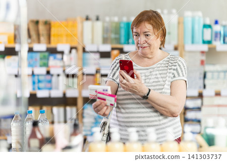 Senior woman in pharmacy scans QR code on paracetamol pills Senior woman in pharmacy scans QR code on paracetamol pills 141303737