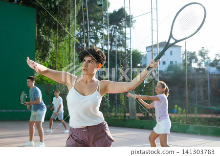 Young hispanic woman playing frontenis on open court in summer Young hispanic woman playing frontenis on open court in summer 141303783
