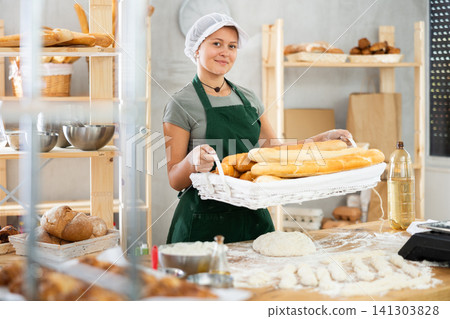 Young woman baker are standing near product range in bakery kitchen. Young woman baker are standing near product range in bakery kitchen. 141303828
