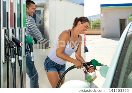 Woman refuelling her car at petrol filling station Woman refuelling her car at petrol filling station 141303833