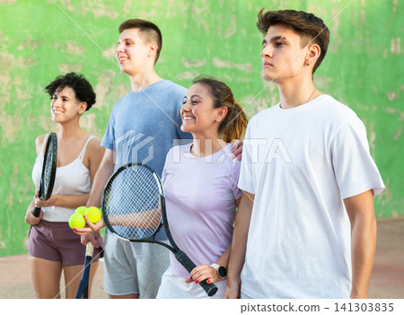 Group photo of positive young men and women standing on frontenis court after game Group photo of positive young men and women standing on frontenis court after game 141303835