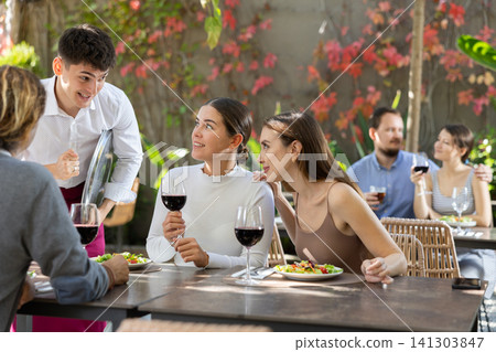 Waiter talking to restaurant guests - taking orders for food and drinks Waiter talking to restaurant guests - taking orders for food and drinks 141303847