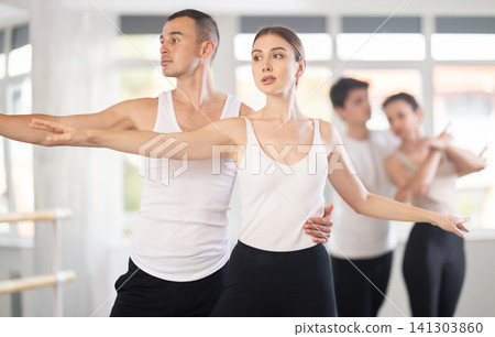 Ballet dancer providing support of female partner in challenging movements Ballet dancer providing support of female partner in challenging movements 141303860