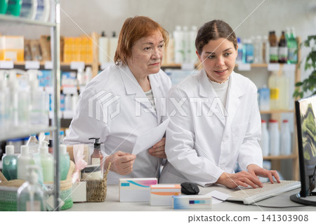 Two female pharmacists checking prescription on computer 141303908
