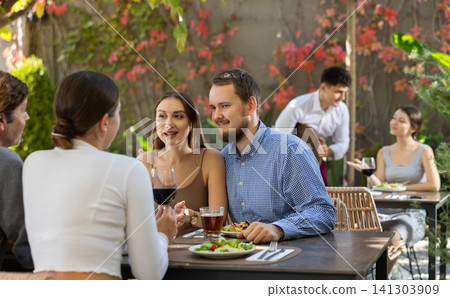 Couples of women and men eating and talking in restaurant Couples of women and men eating and talking in restaurant 141303909
