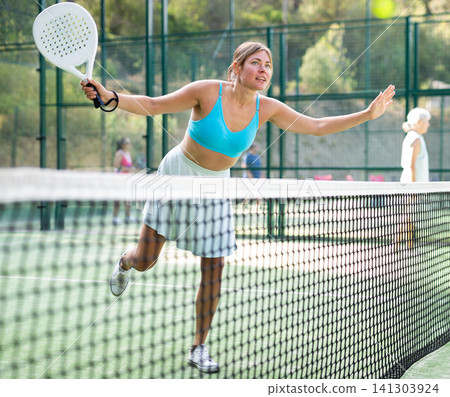 Woman playing padel tennis match during training on court Woman playing padel tennis match during training on court 141303924