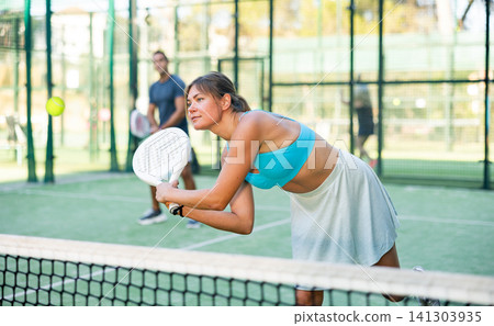 Young woman in skirt playing padel tennis on court 141303935