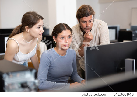 Man and two women discussing at computer 141303946