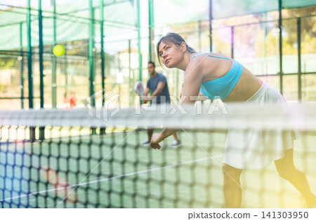 Sporty young woman playing padel on open court on summer Sporty young woman playing padel on open court on summer 141303950