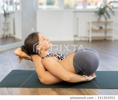 Sporty young girl performing Yogic Sleep Pose 141303952