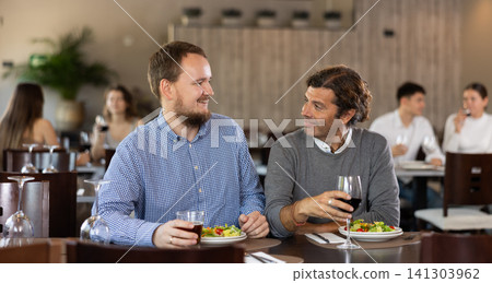 Couple men eating and talking in restaurant Couple men eating and talking in restaurant 141303962