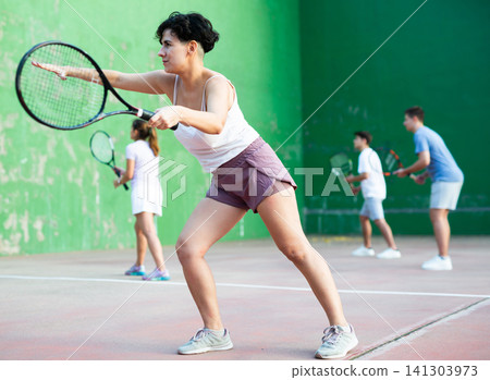 Expressive resolved fit girl playing frontenis ball friendly match on court Expressive resolved fit girl playing frontenis ball friendly match on court 141303973