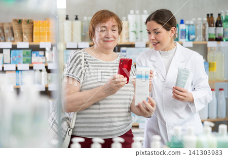 Woman buyer scans cream qr code with woman pharmacist Woman buyer scans cream qr code with woman pharmacist 141303983