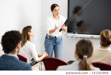 Young female professor explaining subject to classroom full of students Young female professor explaining subject to classroom full of students 141303998