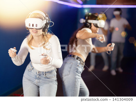 Two girls wearing virtual reality glasses participate in game with opponents Two girls wearing virtual reality glasses participate in game with opponents 141304009