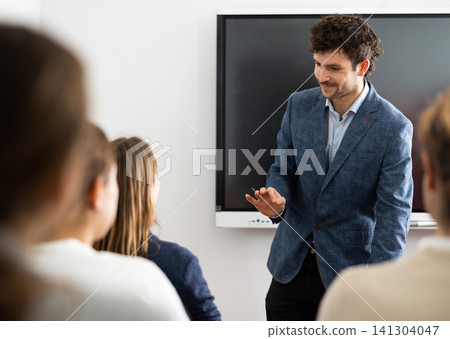 Young male professor explaining subject to classroom full of students Young male professor explaining subject to classroom full of students 141304047
