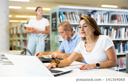 View on a mature man and a young latina student studying together View on a mature man and a young latina student studying together 141304069