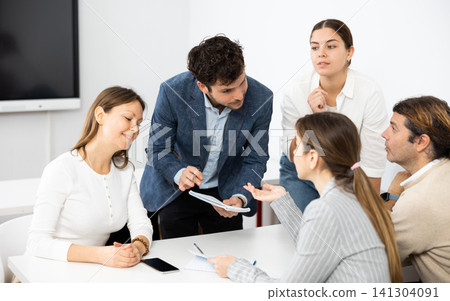Emotional language teacher telling interesting stories to adult attentive students during class break in auditory Emotional language teacher telling interesting stories to adult attentive students during class break in auditory 141304091