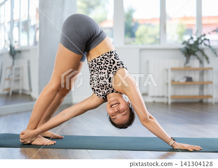 Young woman performing stretching Revolved Downward Facing Dog Pose Young woman performing stretching Revolved Downward Facing Dog Pose 141304128