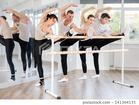 Group of dancers doing stretching at barre Group of dancers doing stretching at barre 141304135
