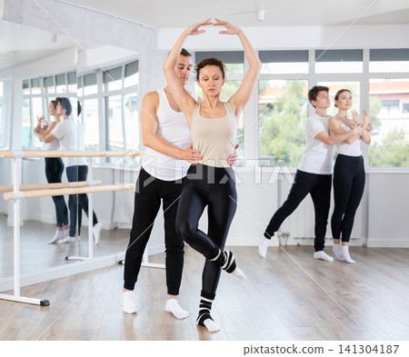 Graceful couple of ballet dancers performing supports at group class Graceful couple of ballet dancers performing supports at group class 141304187