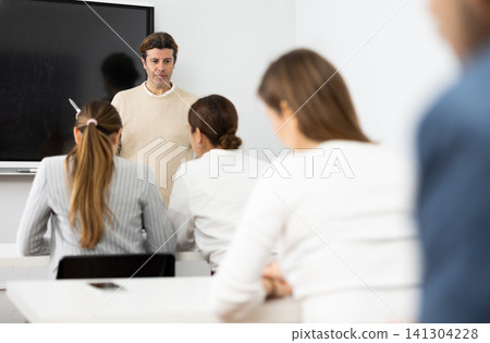 Competent male tutor teaching students in college classroom Competent male tutor teaching students in college classroom 141304228