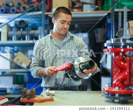 Man using tools to fix sanitary fixture in workshop 141304311