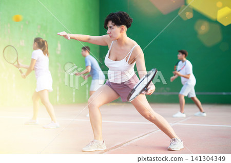 Woman playing frontenis with partners at sunny day, healthy lifestyle concept Woman playing frontenis with partners at sunny day, healthy lifestyle concept 141304349