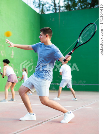 Young man serving ball during frontenis game outdoors Young man serving ball during frontenis game outdoors 141304419