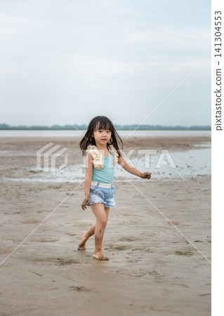 An Asian girl playing on the beach by the river in summer. 141304553