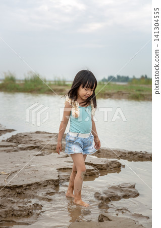An Asian girl playing on the beach by the river in summer. An Asian girl playing on the beach by the river in summer. 141304555