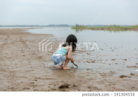 Asian Little Girl Playing with Mud and Water by Riverside 141304558