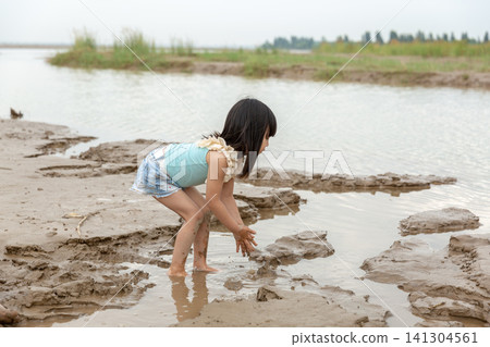 Asian Little Girl Playing with Mud and Water by Riverside 141304561