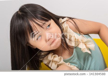 Lovely little Asian girl making a funny, silly face and looking sideways at home. Lovely little Asian girl making a funny, silly face and looking sideways at home. 141304580