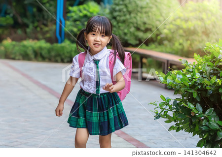 Happy little Asian girl running on the school pathway, joyful student with backpack celebrating back to school. 141304642