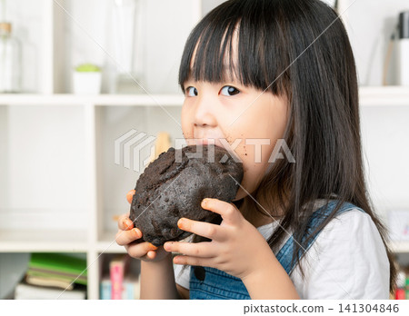 Adorable Asian girl with messy chocolate face eating chocolate cake, sweet tooth and messy eating. Adorable Asian girl with messy chocolate face eating chocolate cake, sweet tooth and messy eating. 141304846